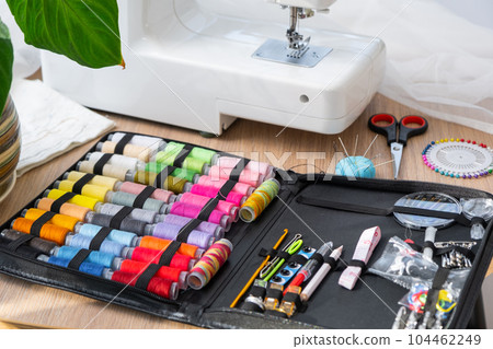 Sewing layout with multicolored spools of thread close-up, needles, electric sewing machine. Filling the thread into the sewing needle, adjusting the tension. hobby, home business 104462249