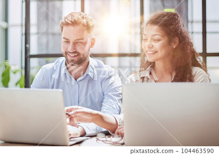 Attractive man and charming woman is pointing at the laptop screen, laughing together, resting 104463590