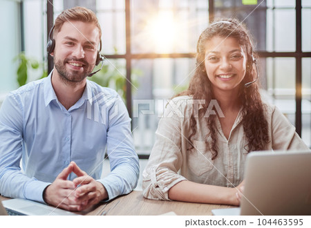 smilling man and charming woman are sitting at laptops in headphones 104463595