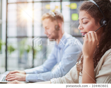 male call-center operator with headphones sitting at modern office 104463601