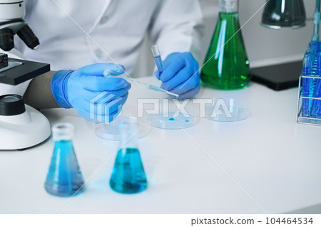 Science and medicine, scientist analyzing and dropping a sample into a glassware, experiments containing chemical liquid in laboratory on glassware, innovative and technology. Science and medicine, scientist analyzing and dropping a sample into a glassware, experiments containing chemical liquid in laboratory on glassware, innovative and technology. 104464534