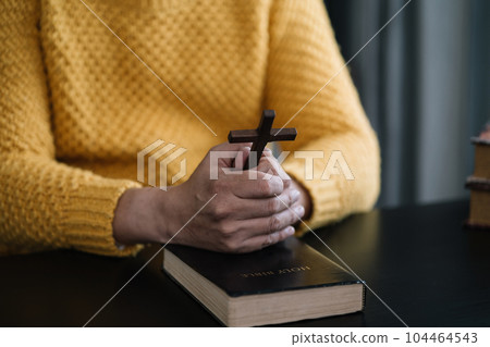 Closeup of simple wooden Christian cross on Bible. Concept of hope, faith, christianity, religion. Closeup of simple wooden Christian cross on Bible. Concept of hope, faith, christianity, religion. 104464543
