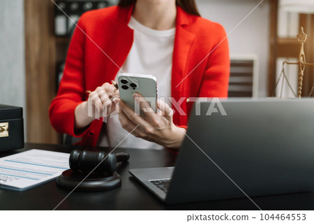 Lawyer office. gavel of Justice with scales and lawyer working on a smartphone and laptop. Legal law, advice and justice concept. Lawyer office. gavel of Justice with scales and lawyer working on a smartphone and laptop. Legal law, advice and justice concept. 104464553