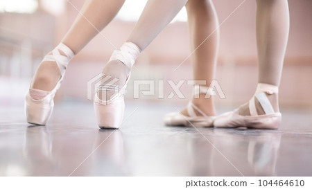Close-up of the legs of two ballerinas in pointe shoes in a dance class. 104464610