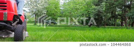 Mower at work on vibrant grass. Copy space web banner. 104464868