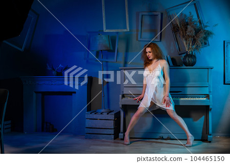 naked woman in a semi transparent white dress near the piano in the studio 104465150