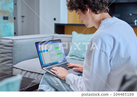 Young male using laptop for chat, sitting resting at home on sofa 104465189