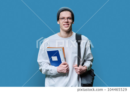 Young guy college student with backpack notebooks textbooks on blue background Young guy college student with backpack notebooks textbooks on blue background 104465529
