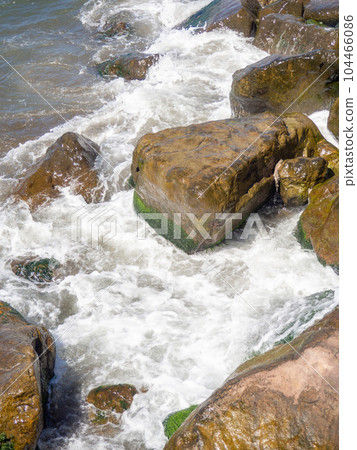 Surf. Waves crash on big rocks. Rocky shore and splashing waves. Powerful coastline. The excitement of the sea. Huge coastal rocks. 104466086