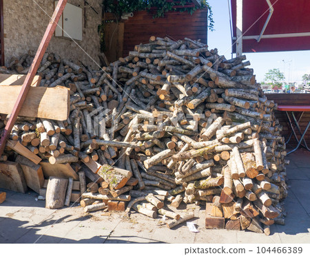 Mountain of firewood in the village. Chopped not thick tree trunks. Stocks for kindling a bath. Mountain of firewood in the village. Chopped not thick tree trunks. Stocks for kindling a bath. 104466389