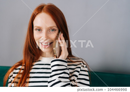 Closeup portrait of pretty young woman talking on smartphone smiling looking at camera. Cheerful female making answering call by cellphone. Positive lady having pleasant conversation speaking by phone 104466998