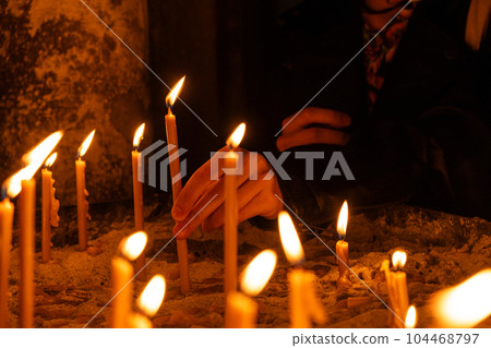 A lot of burning candles in the temple in the dark. The concept of religion, prayer and God. 104468797