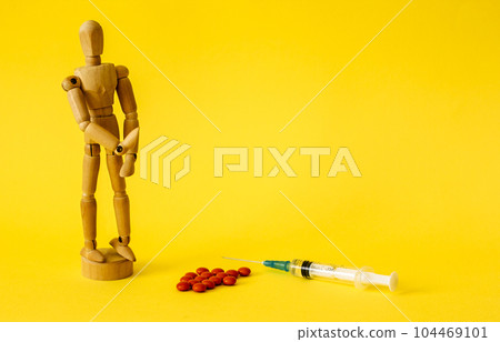 Red pills and injection on a yellow background and a doll Red pills and injection on a yellow background and a doll 104469101