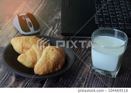 Wireless mouse ,labtop ,a glass of milk and croissants . 104469518
