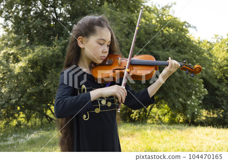 Asian Caucasian Child Plays On Violin, Musical String Instrument, Green Park On Background. Little Adorable Child, Talented Artist, Lifestyle. Horizontal Plane.  104470165