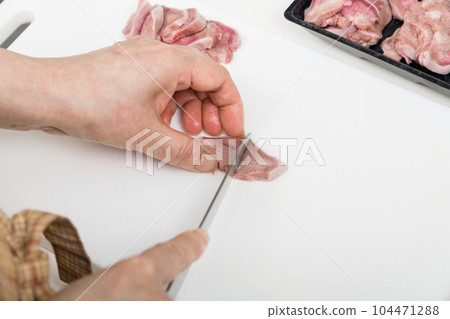 [Housewife preparing yakitori pork tongue with a knife] 104471288