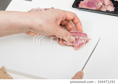 [Housewife preparing yakitori pork tongue with a knife] 104471291