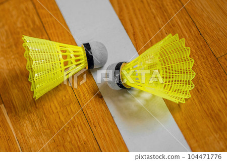 Two plastic shuttlecocks for badminton lie on sports parquet. Background. Badminton game. Two plastic shuttlecocks for badminton lie on sports parquet. Background. Badminton game. 104471776