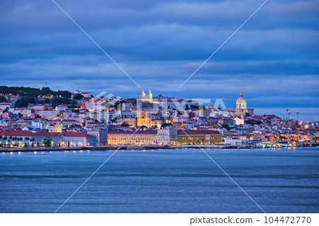 View of Lisbon over Tagus river with passing ferry boat from Almada with ferry in evening twilight. Lisbon, Portugal View of Lisbon over Tagus river with passing ferry boat from Almada with ferry in evening twilight. Lisbon, Portugal 104472770