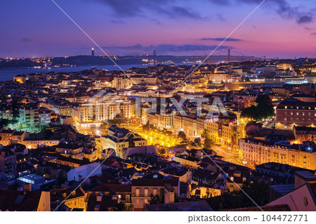 Night view of Lisbon famous view from Miradouro da Senhora do Monte tourist viewpoint of Alfama and Mauraria old city districts, 25th of April Bridge in the evening twilight. Lisbon, Portugal 104472771