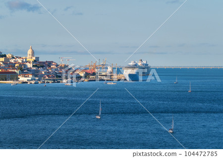 View of Lisbon over Tagus river from Almada with yachts tourist boats and moored cruise liner on sunset. Lisbon, Portugal View of Lisbon over Tagus river from Almada with yachts tourist boats and moored cruise liner on sunset. Lisbon, Portugal 104472785