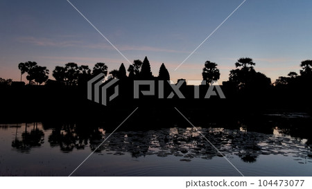 A dusk landscape in Cambodia, with the enigmatic outline of the Angkor Temple and its encompassing region slowly merging with the evening. A dusk landscape in Cambodia, with the enigmatic outline of the Angkor Temple and its encompassing region slowly merging with the evening. 104473077