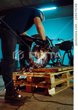 Motorcycle repair. The expert works with electric welding of metal. Instruments and equipment. 104474149