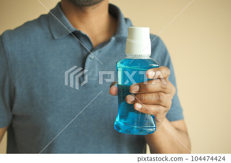 hand hold a mouthwash liquid container  104474424