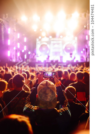 People taking photograph with phone during music festival Fans enjoying rock concert with light show 104474481