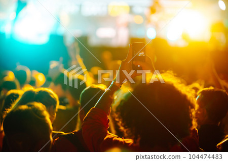 People taking photograph with phone during music festival Fans enjoying rock concert with light show People taking photograph with phone during music festival Fans enjoying rock concert with light show 104474483