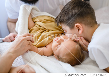 Older brother kiss infant newborn in bed 104474603
