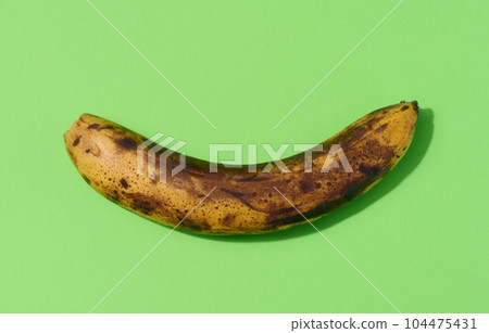 Overripe yellow banana on a green background, top view 104475431