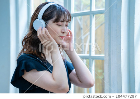 聽到與耳機的音樂的一個少婦 104477297