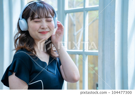 聽到與耳機的音樂的一個少婦 104477300