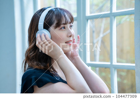 聽到與耳機的音樂的一個少婦 104477309