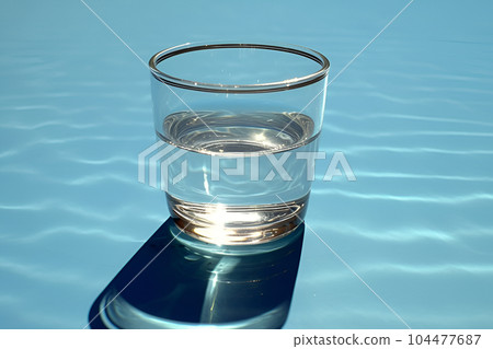 Glass of drinking water isolated on blue background 104477687