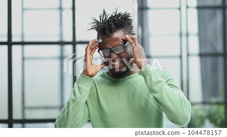 african american man in a green shirt holding his hands behind his head african american man in a green shirt holding his hands behind his head 104478157