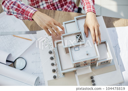 Male architect holding and working on model of architectural house top view 104478819