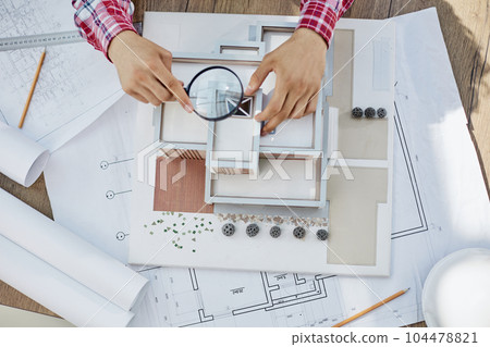 Male architect holding and working on model of architectural house top view 104478821