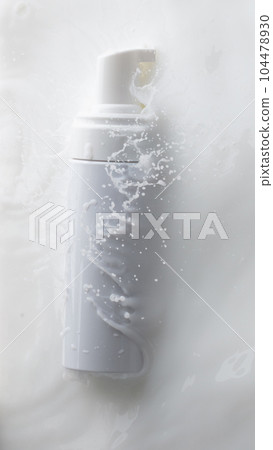 Cosmetic container white lotion droplet fly splashing. Milk lotion pour float to cosmetic bottle. Moisturizer lotion explosion spill. White background isolated high speed shutter freeze top view Cosmetic container white lotion droplet fly splashing. Milk lotion pour float to cosmetic bottle. Moisturizer lotion explosion spill. White background isolated high speed shutter freeze top view 104478930