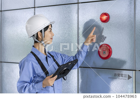 一名身穿工作服的婦女檢查火災報警大樓維護圖像 一名身穿工作服的婦女檢查火災報警大樓維護圖像 104478963