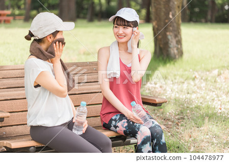 Asian woman sitting on a park bench and resting during exercise, aerobic exercise, running in the park 104478977