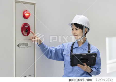 一名身穿工作服的婦女檢查火災報警大樓維護圖像 一名身穿工作服的婦女檢查火災報警大樓維護圖像 104479048
