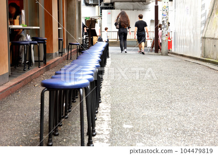 Chairs for waiting customers lined up in front of a busy store Chairs for waiting customers lined up in front of a busy store 104479819
