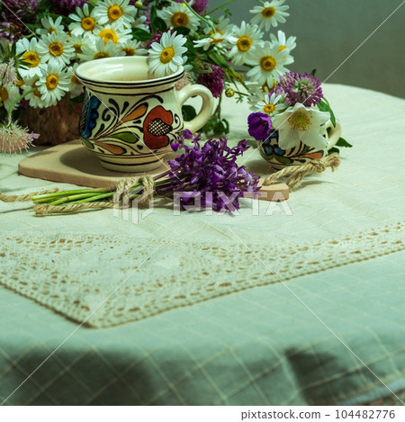 A cup of coffee and spring wildflowers on a white tablecloth. 104482776