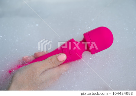 Woman lies in a bubble bath and uses a vibrator. Woman lies in a bubble bath and uses a vibrator. 104484098
