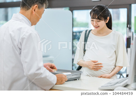 A pregnant woman who visits a pharmacy and a pharmacist who instructs her on how to take her medication A pregnant woman who visits a pharmacy and a pharmacist who instructs her on how to take her medication 104484459