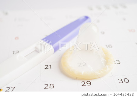 Pregnancy test and condom for female on calendar, ovulation day. Pregnancy test and condom for female on calendar, ovulation day. 104485458