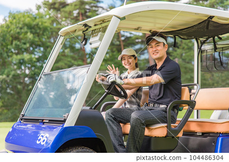 Golfer man and woman riding a golf cart on a golf course Golfer man and woman riding a golf cart on a golf course 104486304