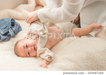 baby getting dressed by mom baby getting dressed by mom 104487260